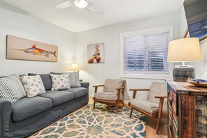 A living room with a grey sofa, striped armchairs, a patterned rug, and artwork on the walls. - New Listing -- 3 BR Oceanfront Condo in Duck with pool (Duck)