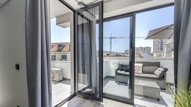 A modern balcony with a glass door, a sofa, and a small table.