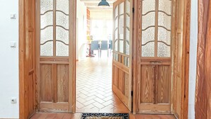 Une porte d’entrée en bois avec des panneaux de verre et un sol carrelé disposé en motif de chevrons.