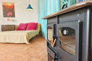 A room with a bed, a dresser, and a vintage stove.