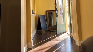 Un pasillo con piso de madera, ventilador de techo y puerta con panel de vidrio.