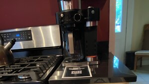 Una cocina con cafetera, estufa y un cajón con filtros de café y azúcar.