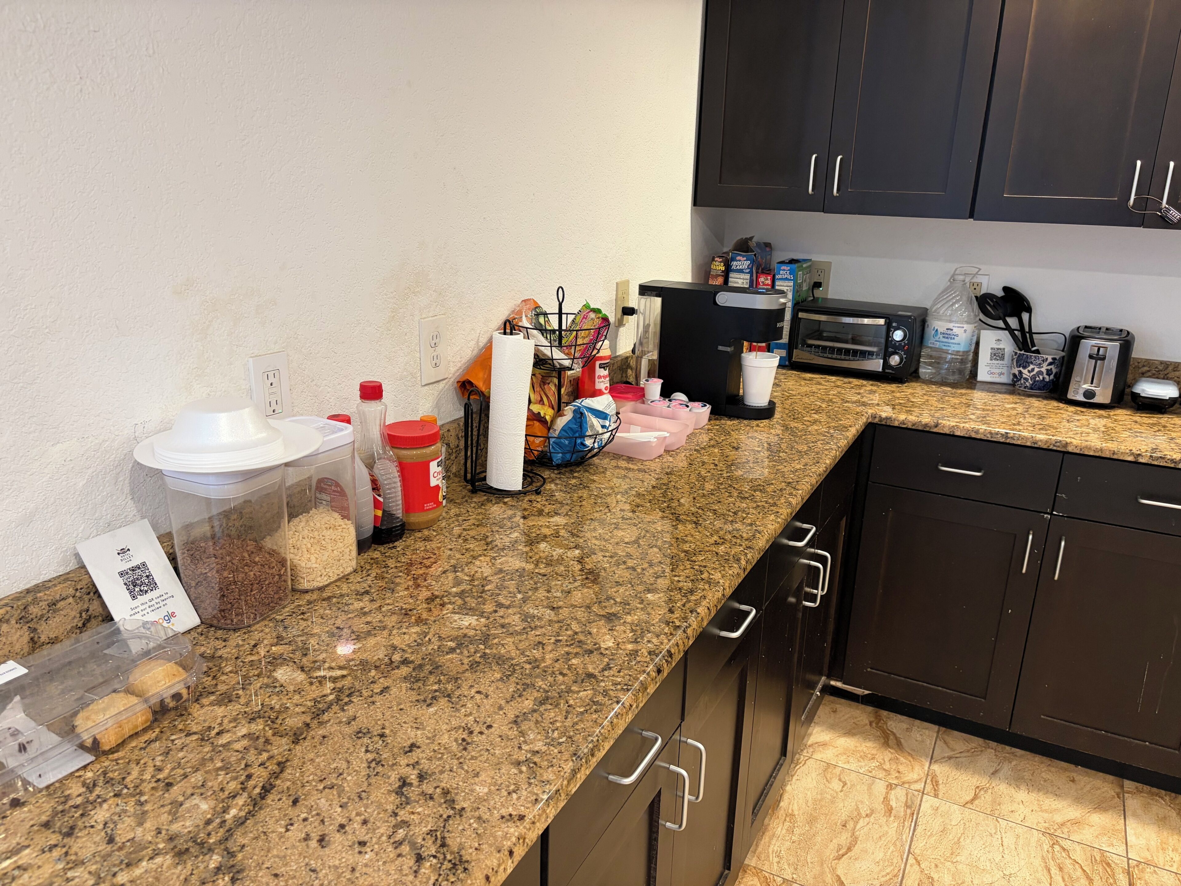 A kitchen with granite countertops, a coffee maker, a toaster, and various kitchen items.