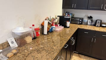 A kitchen with granite countertops, a coffee maker, a toaster, and various kitchen items.