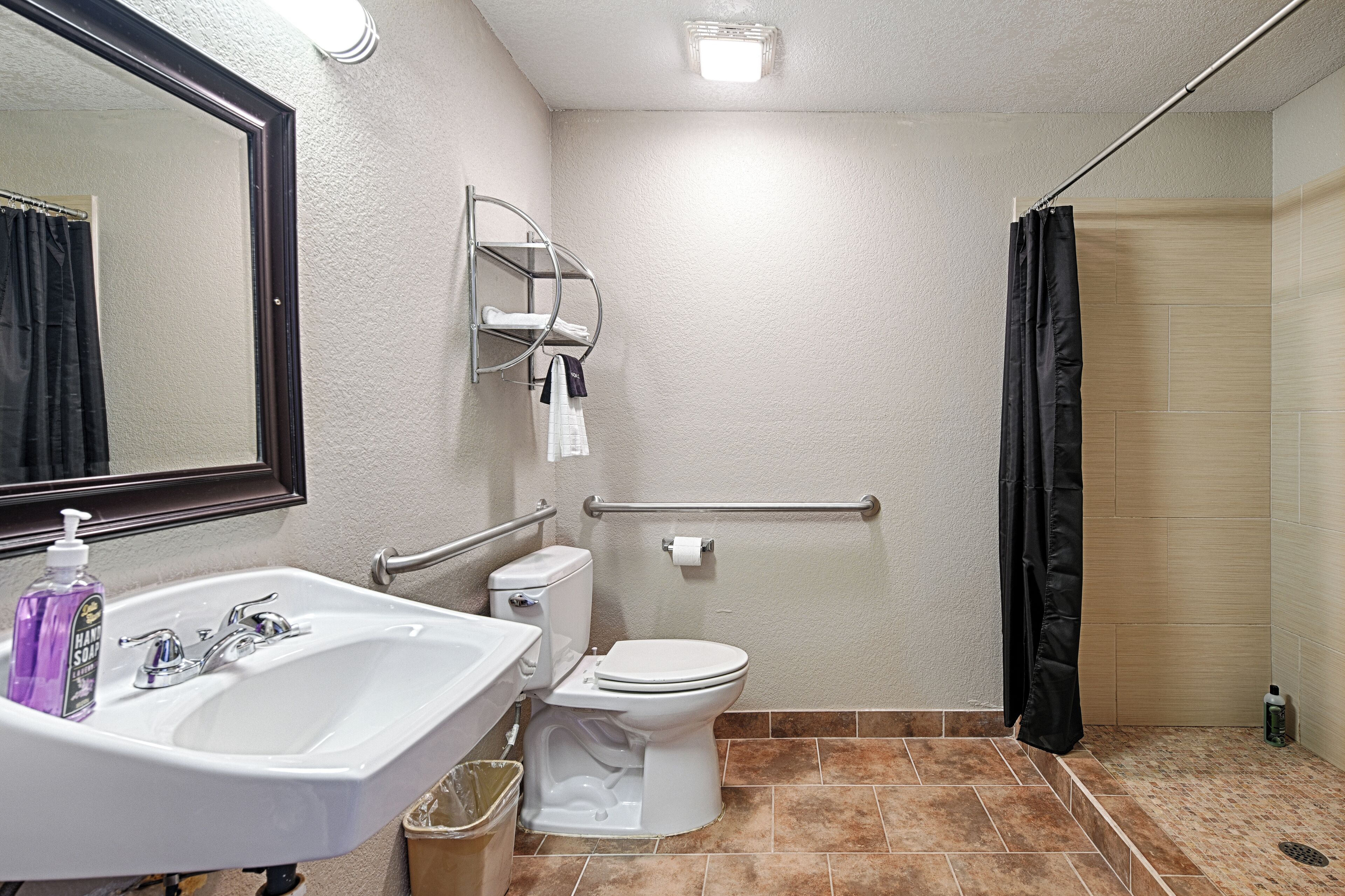 A bathroom with a sink, toilet, mirror, and shower.