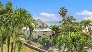 A coastal property with a white building, palm trees, and a view of the sea. - Renovated Apartment with pool at the garden #6 (Pelican Key)