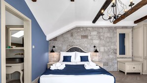 Un dormitorio con una cama grande, pared de piedra y una araña.