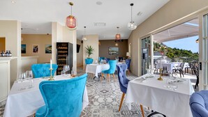 Un restaurante con sillas azules, mesas blancas y un suelo estampado.
