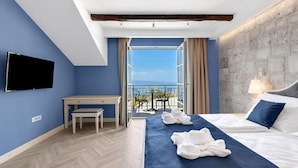 Een hotelkamer met een bed, een bureau, een stoel, een televisie en een balkon met uitzicht.