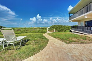A pathway leading to a beach with a chair and a building with a balcony. - Directly on the Gulf - Unit 3 - 1 Bedroom - Ground Floor - Sleeps up to 5 (Venice)