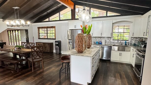 A spacious kitchen with white cabinets, a central island, and a dining area with wooden furniture. - Unique Spanish Style Lakefront Home!  Kayaks and Paddle Boat! (Keystone Heights)