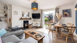 A modern living room with a sofa, coffee table, and dining area with chairs. - Cute & Cosy Cottage | Chilterns - Pass the Keys (Princes Risborough)