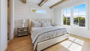 A bedroom with a large bed, wooden beams, a skylight, and a view of the outdoors. - AMI Escape! Swim-Up Bar, Ping Pong, Spa and Walk to Beach (Anna Maria)