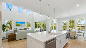 A spacious kitchen with a large island, white cabinetry, and pendant lighting. - AMI Escape! Swim-Up Bar, Ping Pong, Spa and Walk to Beach (Anna Maria)