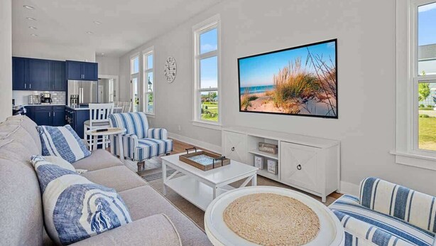 Ein modernes Wohnzimmer mit einer Couch, gestreiften Sesseln, einem Couchtisch und einem Fernseher.