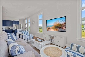 Uma sala de estar moderna com um sofá, cadeiras listradas, uma mesa de centro e uma televisão.