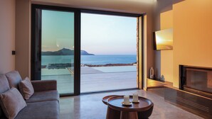Een moderne woonkamer met een grote schuifpui die uitkomt op een balkon met uitzicht op zee.