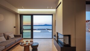 Een moderne woonkamer met een grote schuifpui die uitkomt op een balkon met uitzicht op zee en bergen.