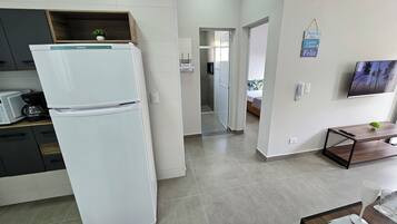 Eine moderne Küche mit einem weißen Kühlschrank, einer Kaffeemaschine und einem kleinen Topf mit Pflanze auf der Arbeitsfläche.