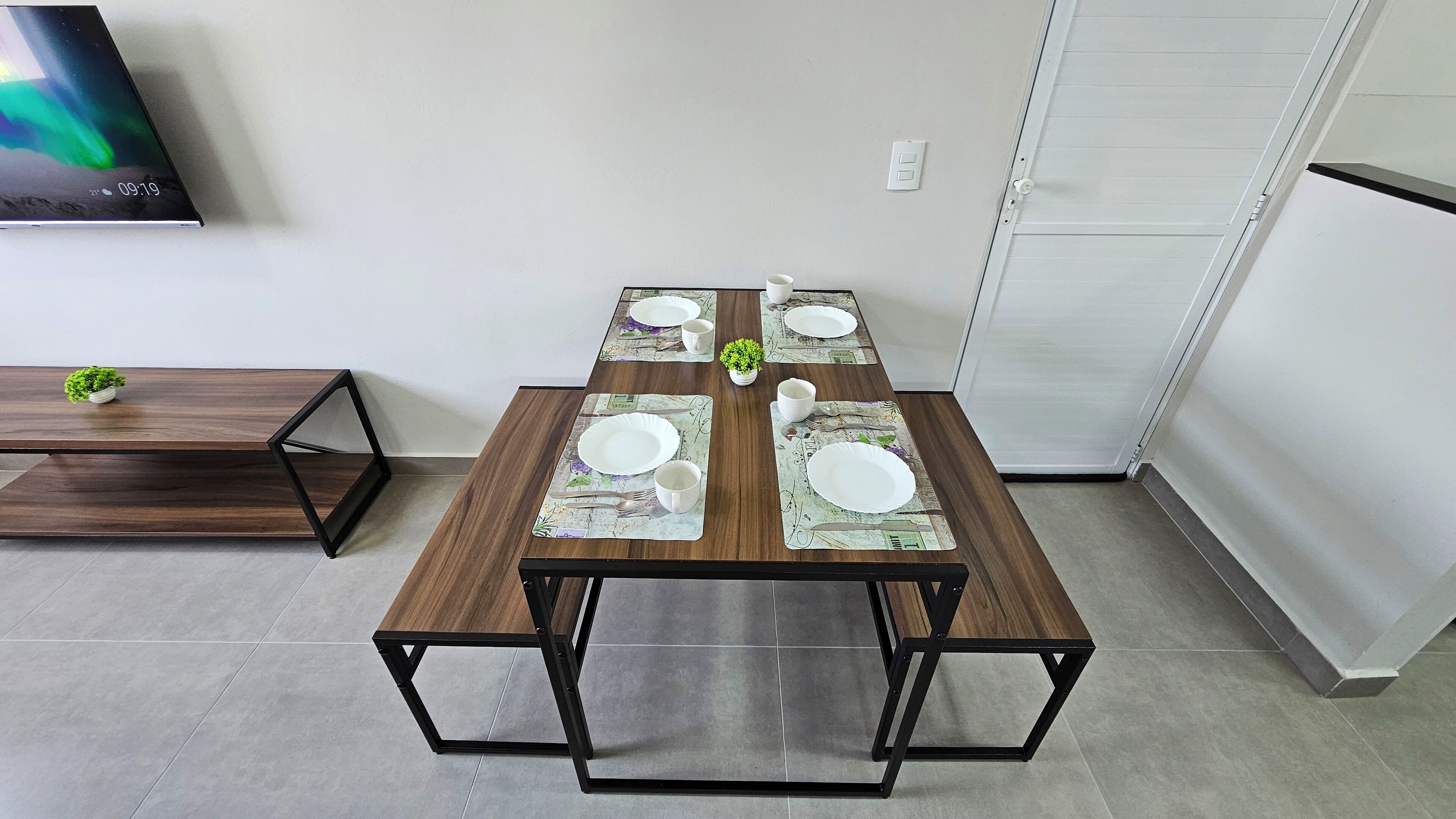 A dining table set with plates, cups, and a small potted plant.
