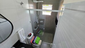 A compact bathroom with a glass shower enclosure, a toilet, and a sink. - Spazio Italia Apartamentos (Ilha Comprida)
