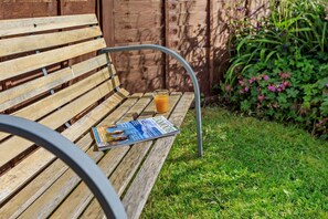 Un banco de madera con una revista y un vaso de jugo de naranja.