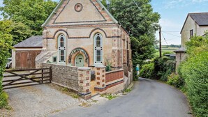 A brick building with a triangular roof, arched windows, and a small door. - 2 Bed in Goodleigh (oc-l29573) (Goodleigh)