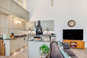 Una cocina moderna con una isla central, un área de comedor con sofá y un televisor de pantalla plana.
