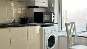 Una cocina equipada con lavadora, microondas y ventana.