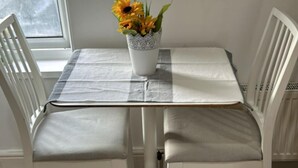 Una mesa blanca con mantel a cuadros gris y blanco, rodeada de sillas blancas.