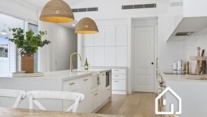 Une cuisine moderne avec des meubles blancs, un îlot central et des luminaires suspendus.