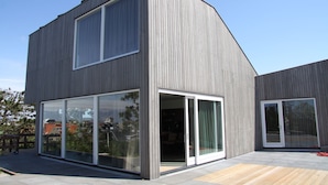 A modern two-story building with large glass windows and sliding glass doors.