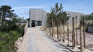 A modern building with a gravel pathway leading to a glass door entrance.