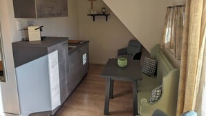 Une cuisine compacte au design moderne, un coin repas avec une table et des chaises, et un petit espace détente avec un canapé.