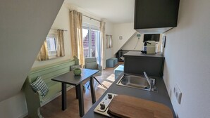Une cuisine compacte comprenant un évier, une planche à découper en bois et un coin repas avec une table et des chaises.