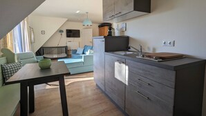 Un espace de vie compact comprenant un coin cuisine, un coin repas et un espace détente avec un canapé et un lit bébé.