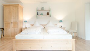 Une chambre à coucher avec un lit en bois, deux tables de chevet avec des lampes, une armoire et une étagère avec des objets décoratifs.