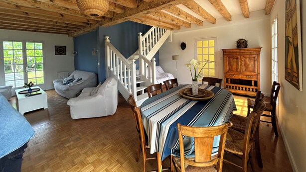 Un vaste espace de vie comprenant une table à manger, des chaises et un escalier menant à un autre niveau.
