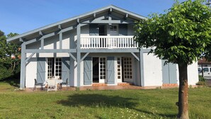 Une maison à deux étages dotée d’un balcon, d’un porche et d’un petit jardin.