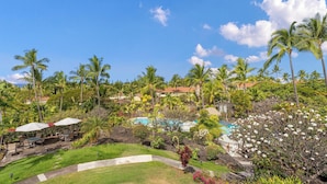 Un resort tropical con piscina, palmeras y zonas de estar al aire libre.