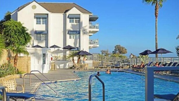 A hotel with a swimming pool, lounge chairs, and umbrellas. - Dana Point Beach front condo with balcony (Dana Point)
