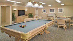 A pool table with balls, a television, and a seating area with chairs and a sofa. - Dana Point Beach front condo with balcony (Dana Point)