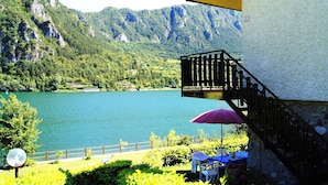 Ein Balkon mit Blick auf einen See und Berge, eine Holzlattenveranda und ein Tisch mit einem Stuhl.