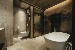 Un baño moderno con una bañera independiente, un inodoro y una zona de ducha.