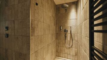 A modern shower with a handheld showerhead and a wall-mounted faucet.