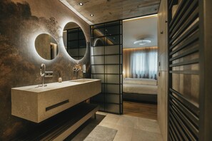 Un baño moderno con un lavamanos grande, dos espejos y un techo de madera.