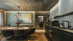 Een moderne keuken met donkere kasten, een centraal eiland en een eethoek met een houten tafel en stoelen.