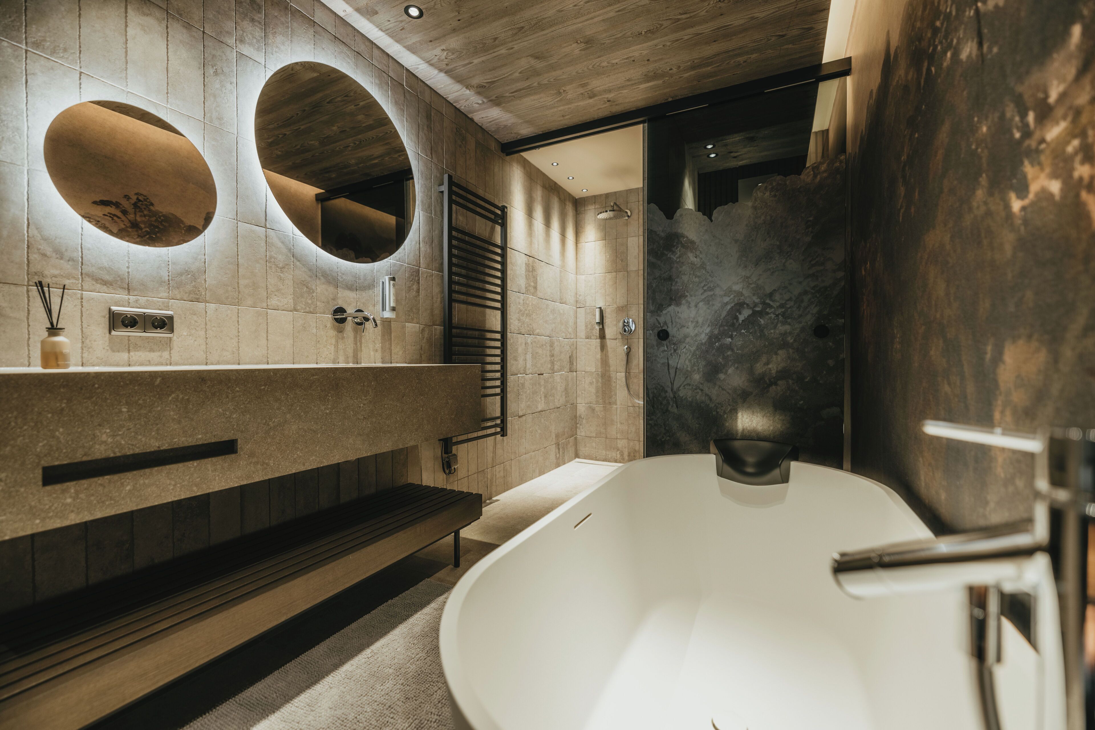 Une salle de bain moderne avec une baignoire sur pieds, un lambris en bois et deux miroirs ovales.