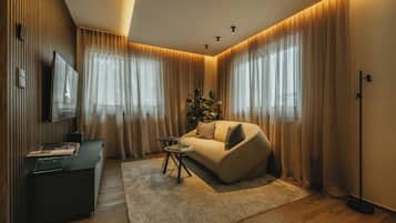 A modern living room with a sofa, a coffee table, a TV, and a plant.