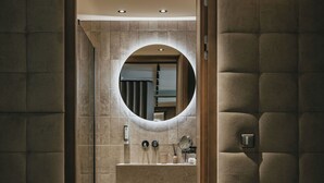 Een moderne badkamer met een ronde spiegel, een wastafel en een toilet.